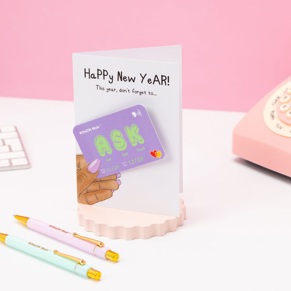 Happy New Year card with a phone and stationery items on a pink background
